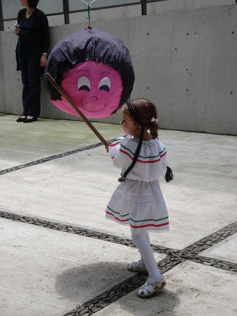 "ein mexikanisches Kind in einem schicken Klein, natürlich mit den Mexiko-Farben, beim Einschlagen auf die Pinata"